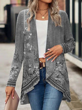 Woman wearing a gray floral draped cardigan with long sleeves, white crop top, and blue jeans