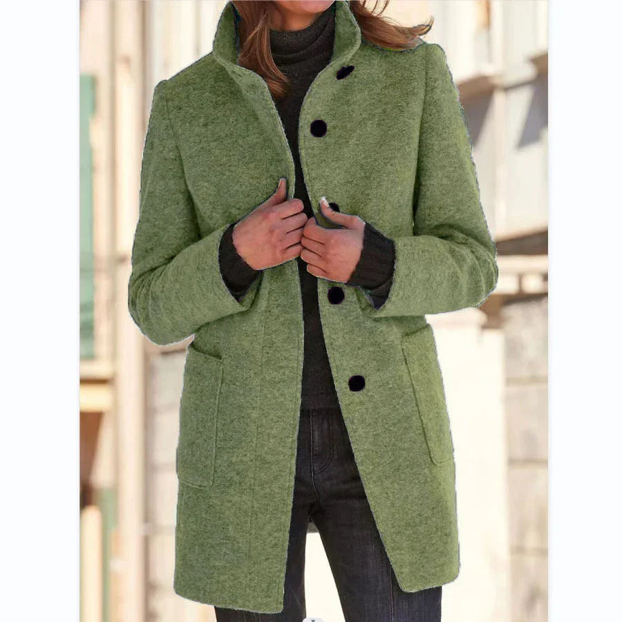 Woman wearing a light green wool blend coat with black buttons, tailored fit, street style