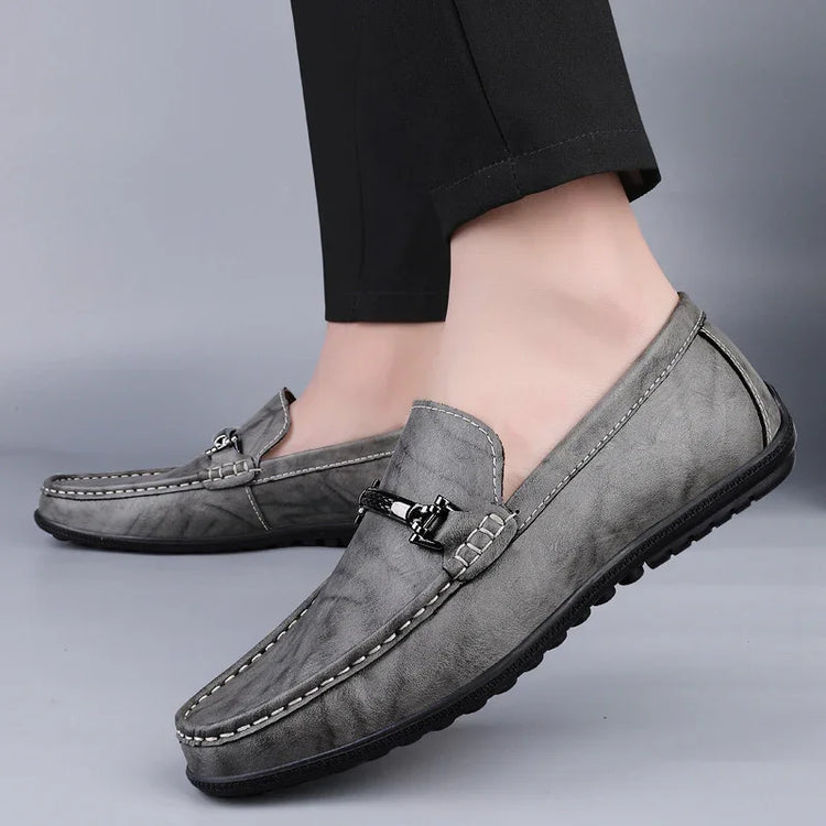 Gray leather loafers with metal buckle, textured finish, and casual slip-on fit