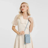 Woman wearing cream puff sleeve dress with sheer embroidered sleeves and a light blue crossbody bag