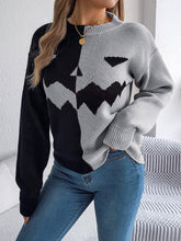 Woman wearing a colorblock knit sweater with black and gray zigzag pattern, relaxed fit, paired with jeans.