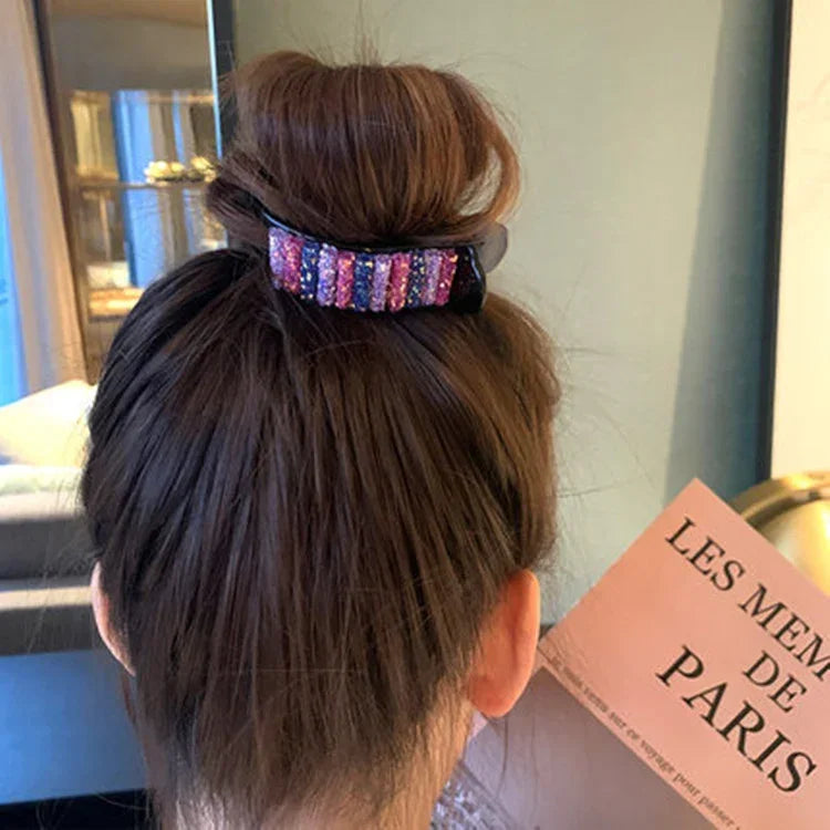 Woman with brown hair in a bun secured by a multicolored rhinestone hair clip