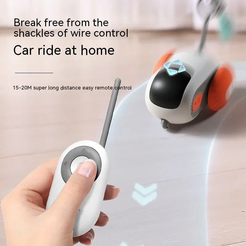 Hand holding wireless remote control for toy car with orange wheels on wooden floor