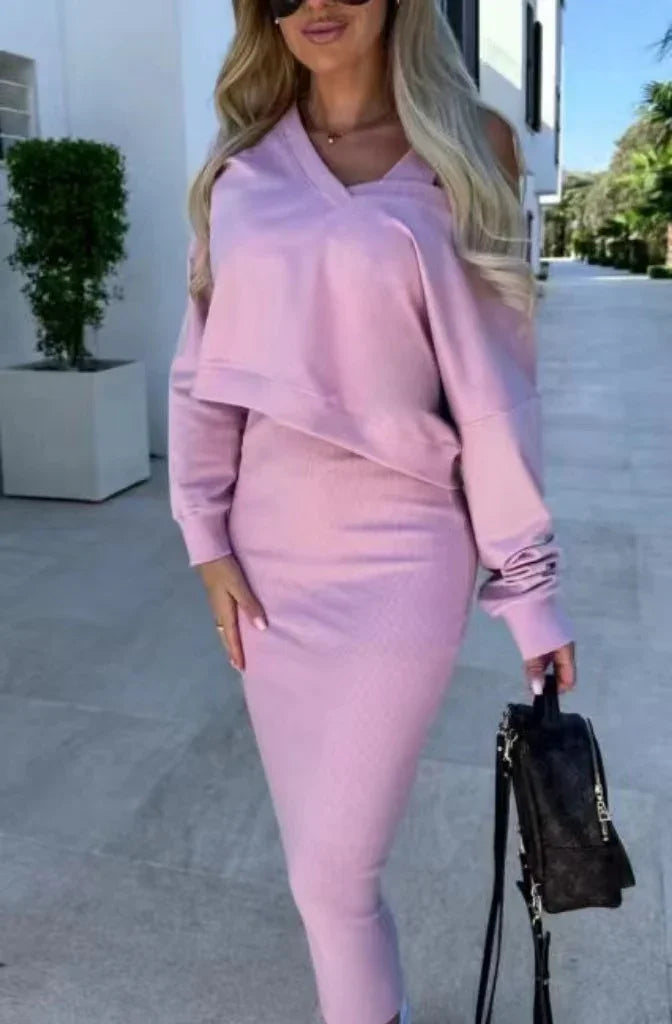Woman wearing a light pink, fitted knit skirt and matching long sleeve top, streetwear style.