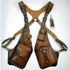 Brown leather shoulder holster harness with brass hardware and adjustable fit.