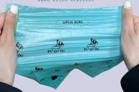 Hands holding a blue, semi-transparent plastic bag with cartoon dog prints and easy-tear opening.