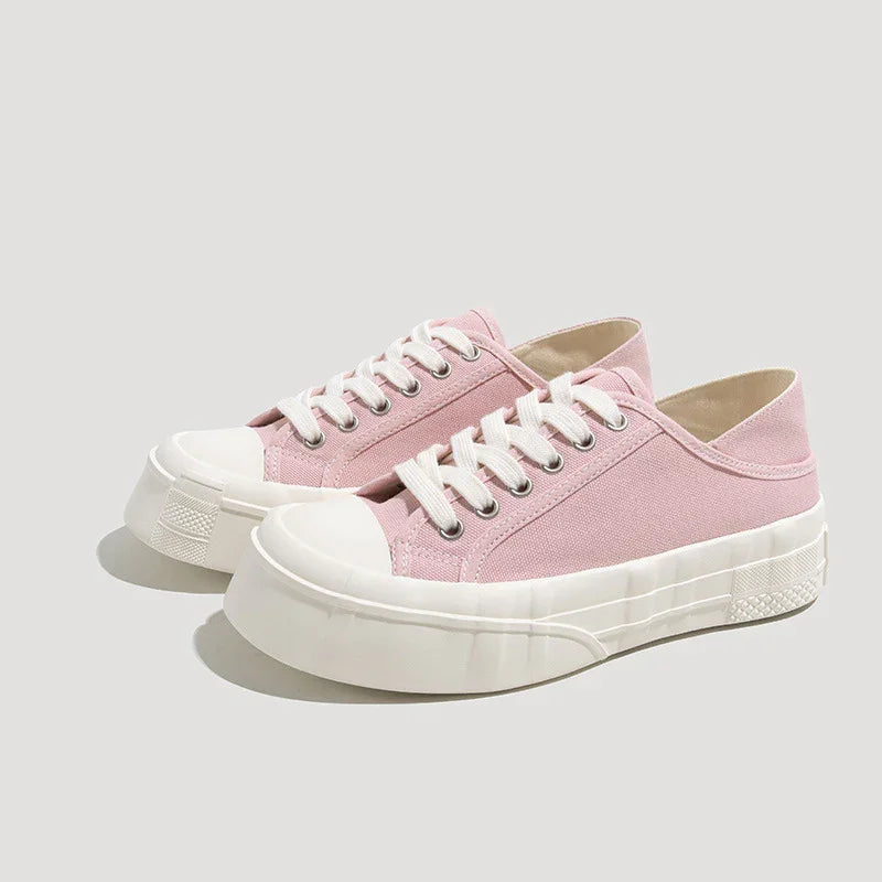 Light pink canvas low-top sneakers with chunky white rubber soles and metal eyelets
