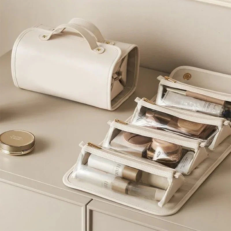 Beige faux leather travel cosmetic bag with clear zippered compartments, organized on a vanity