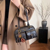 Woman wearing an oversized tan trench coat with a black leather shoulder bag and front pockets.