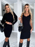 Woman modeling black ribbed knit mini dress, fitted silhouette, long sleeves and sleeveless options, paired with knee-high boots and a black shoulder bag, in a modern indoor setting.
