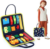 Child wearing rust orange turtleneck and pants with a cream cable knit vest, holding a colorful sensory busy board bag featuring interactive buckles, zippers, and buttons.
