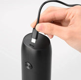 Hand plugging USB-C cable into matte black portable electronic device