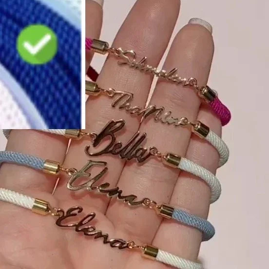 Hand holding multiple personalized name bracelets with colored cord and gold-tone metal accents