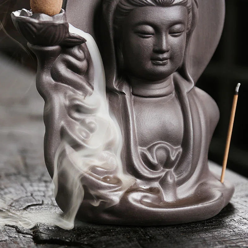 Close-up of a ceramic incense holder shaped like a serene figure with flowing smoke