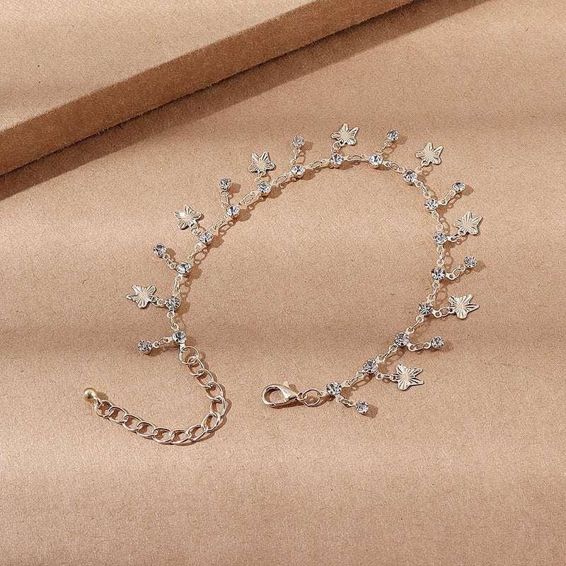 Delicate gold chain bracelet with flower charms and crystal accents on a neutral background.