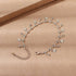 Delicate gold chain bracelet with flower charms and crystal accents on a neutral background.
