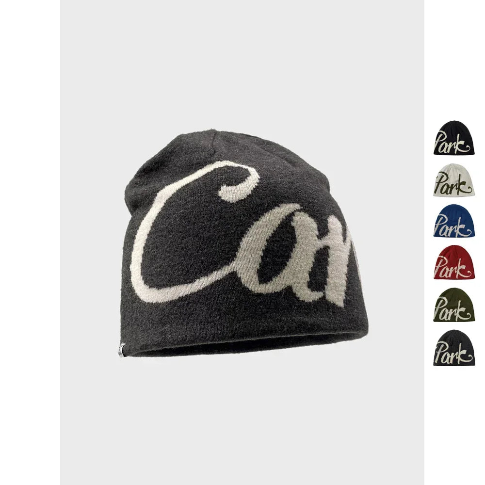 Black knit beanie with bold white script text, relaxed fit, displayed with color options