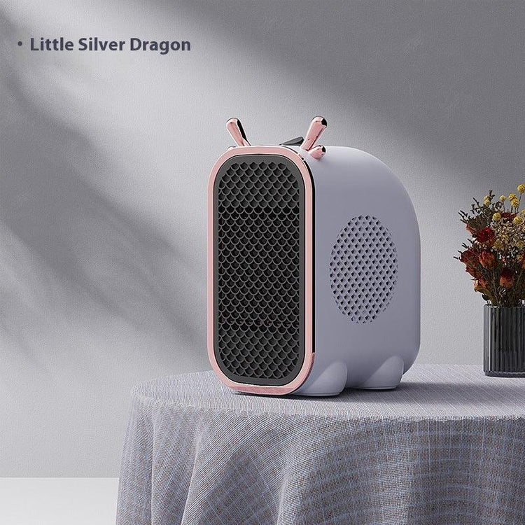 Compact modern space heater in pastel pink and grey, rounded design, sits on textured tablecloth.