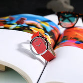 Modern red leather wristwatch with open face design on a colorful magazine background