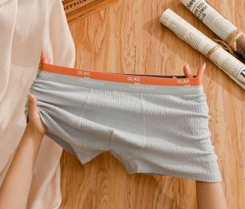 Light gray men's boxer briefs with textured fabric and stretchy fit, displayed on wood surface