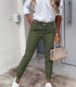 Woman wearing olive green slim-fit jogger pants, white button-up shirt, and white sneakers