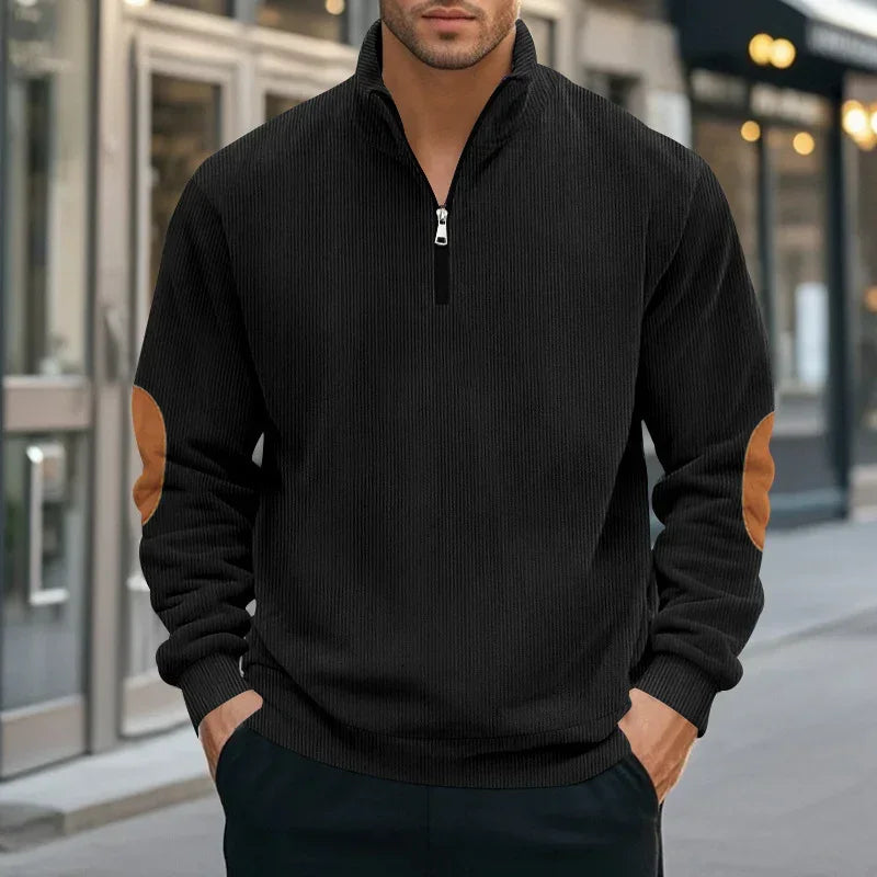 Men's black quarter-zip sweater with ribbed texture and tan suede elbow patches, relaxed fit.