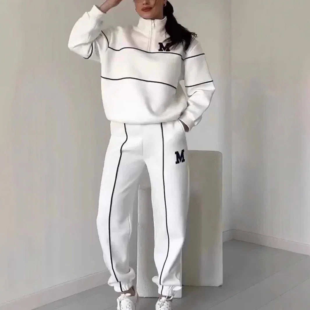 Woman in white relaxed-fit tracksuit with black piping and zip collar, sporty streetwear style