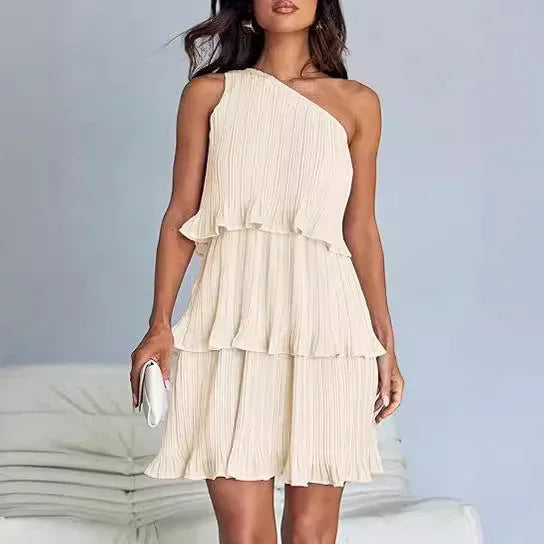 Woman wearing a cream pleated one-shoulder tiered mini dress with relaxed fit