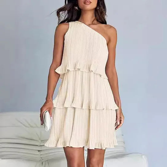 Woman wearing a cream pleated one-shoulder tiered mini dress with relaxed fit