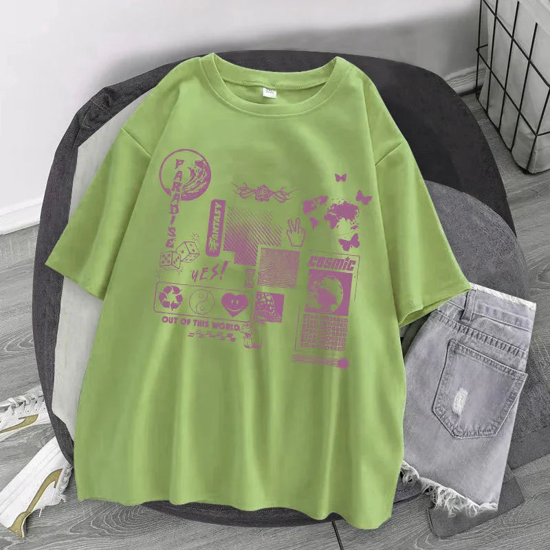 Light green oversized graphic t-shirt with purple streetwear prints, paired with ripped denim shorts.