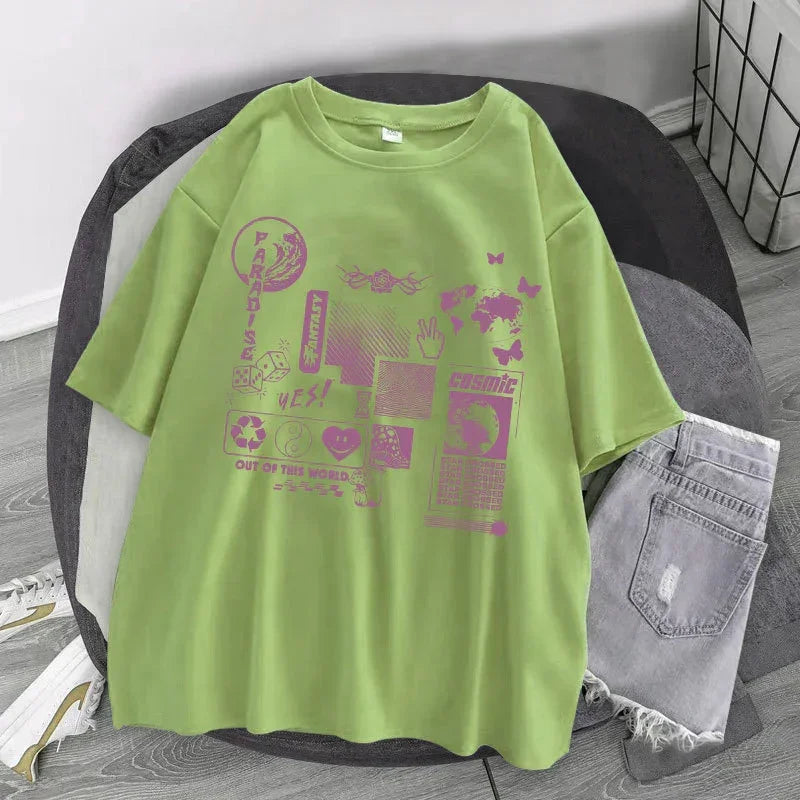 Light green oversized graphic t-shirt with purple streetwear prints, paired with ripped denim shorts.