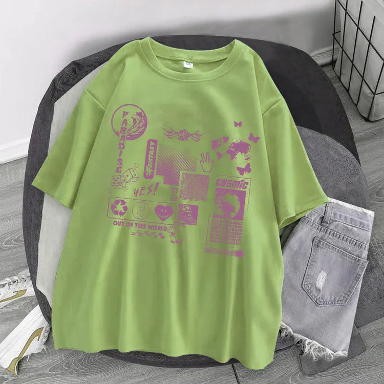 Light green oversized graphic t-shirt with purple streetwear prints, paired with ripped denim shorts.