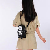 Woman in a beige short-sleeve romper carrying a black skeleton crossbody bag