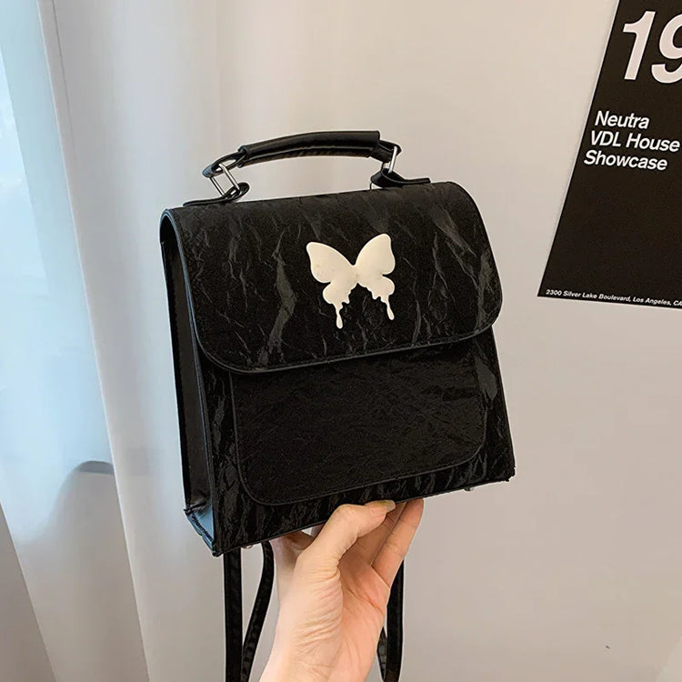 Black faux leather mini backpack with white butterfly graphic and top handle, streetwear style