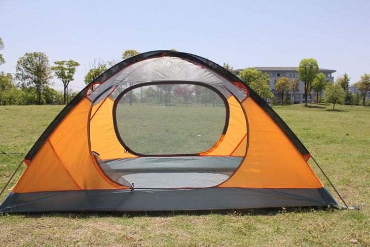 Orange and gray dome tent with mesh panels pitched on grass in sunny outdoor setting
