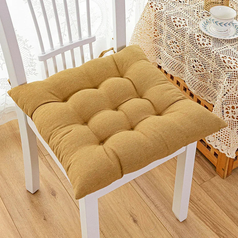 Soft tufted mustard yellow cotton cushion on a white chair, cozy home decor setting