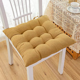Soft tufted mustard yellow cotton cushion on a white chair, cozy home decor setting