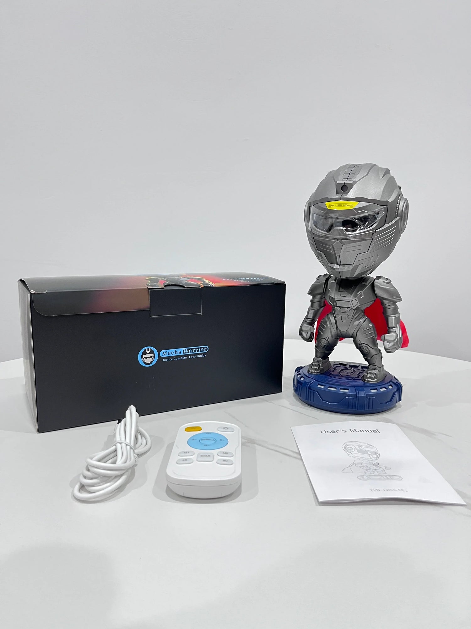 Robot figure with metallic gray armor and red cape, shown with remote and manual on table