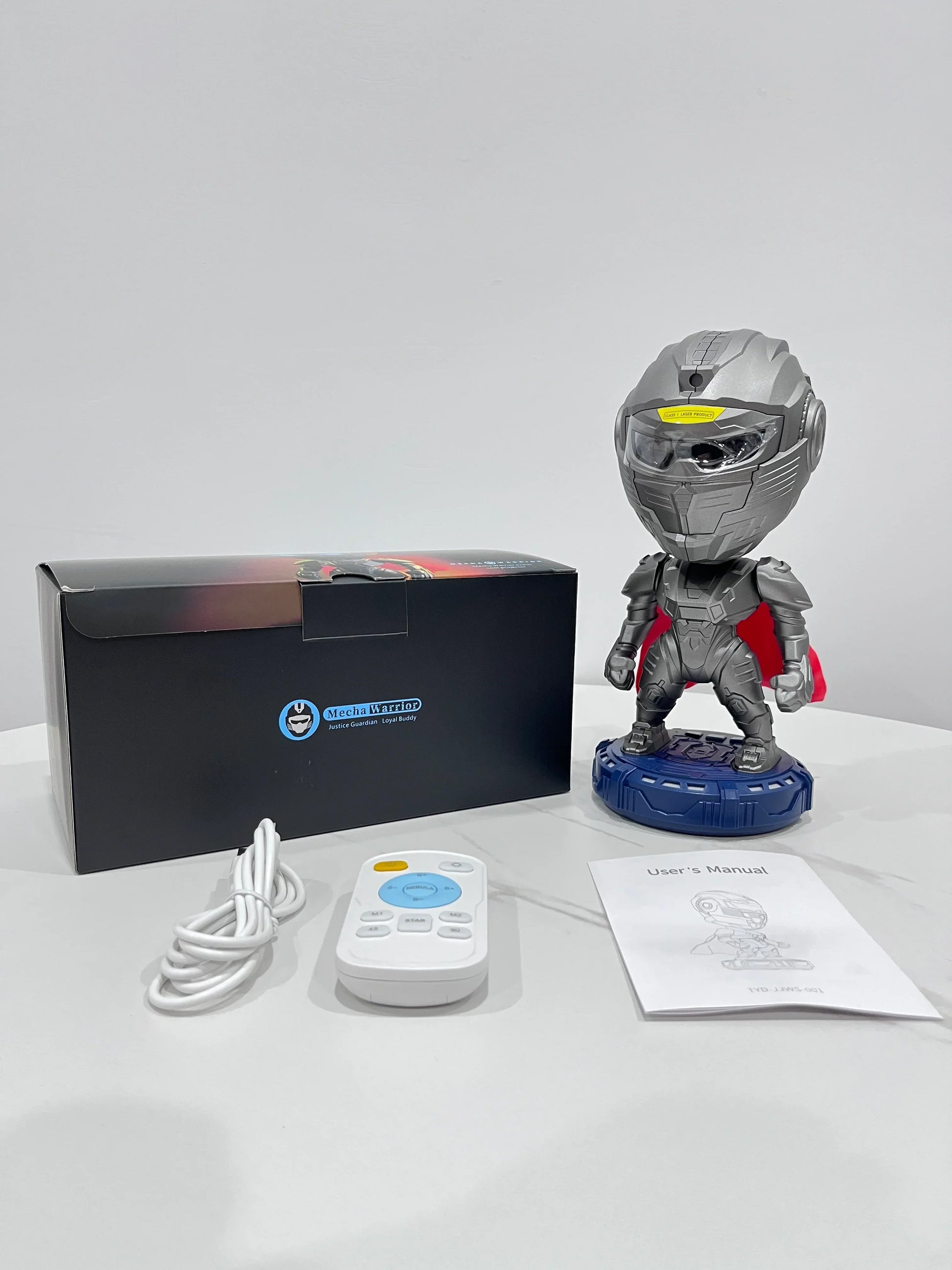 Robot figure with metallic gray armor and red cape, shown with remote and manual on table
