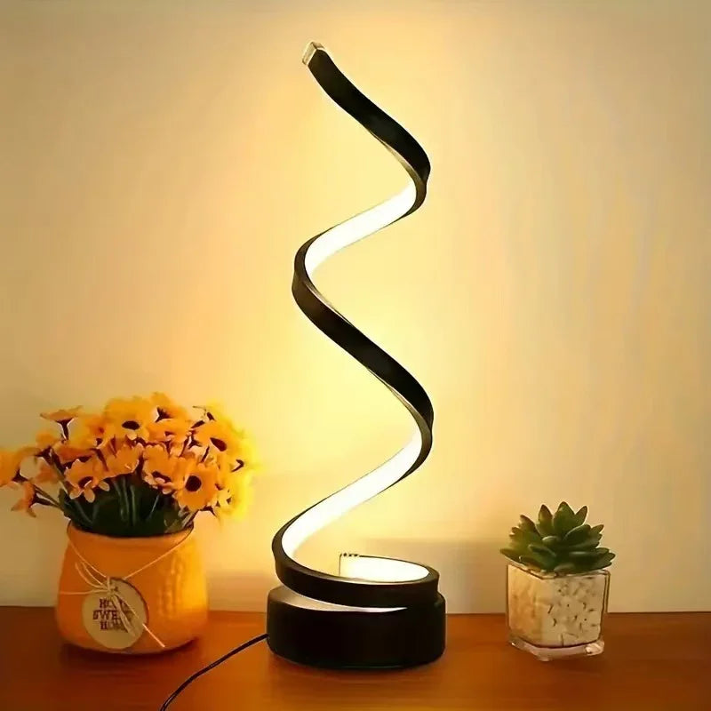 Modern spiral LED table lamp with black metal and warm white light on wooden surface