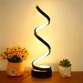 Modern spiral LED table lamp with black metal and warm white light on wooden surface