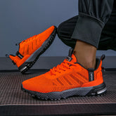 Bright orange knit athletic sneakers with black soles and mesh pattern, worn with jogger pants