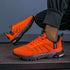 Bright orange knit athletic sneakers with black soles and mesh pattern, worn with jogger pants