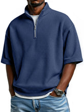 Man wearing blue waffle-textured half-zip shirt with loose fit and casual jeans
