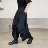 Man wearing loose black wide-leg cargo pants with pleats, paired with black shoes