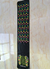 Black acupressure massage mat with multicolored raised stones for foot reflexology