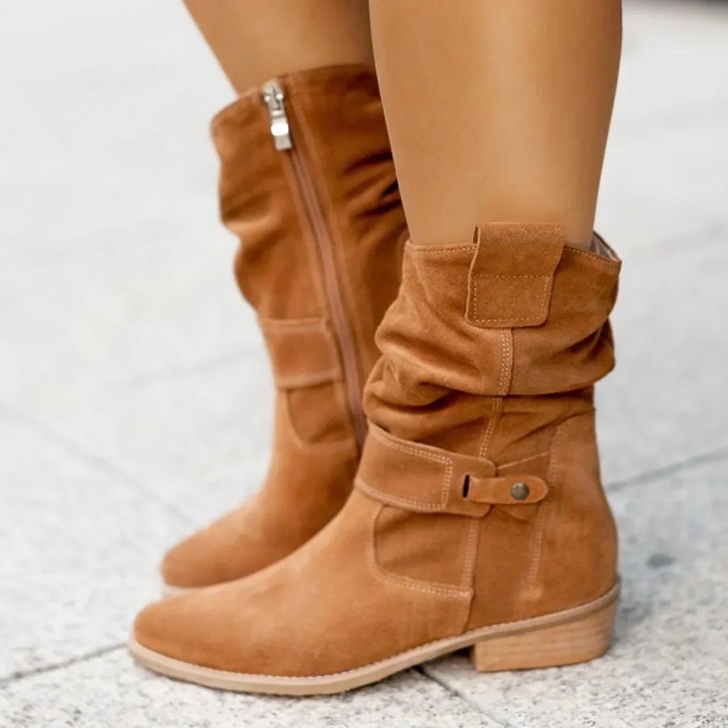 Tan suede mid-calf boots with slouchy fit, side zipper, and decorative strap detail
