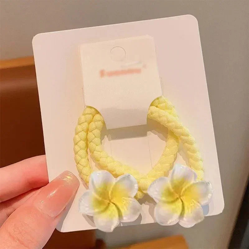 Yellow braided fabric hair ties with white and yellow flower accents on display card