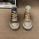 Mismatched denim high-top sneakers with gold laces and vintage wash on carpet