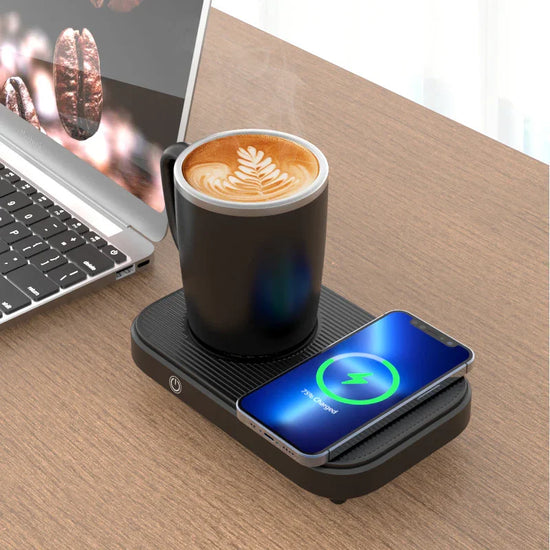 Black ceramic mug with latte art on a mug warmer, wireless phone charger, and laptop on wooden desk